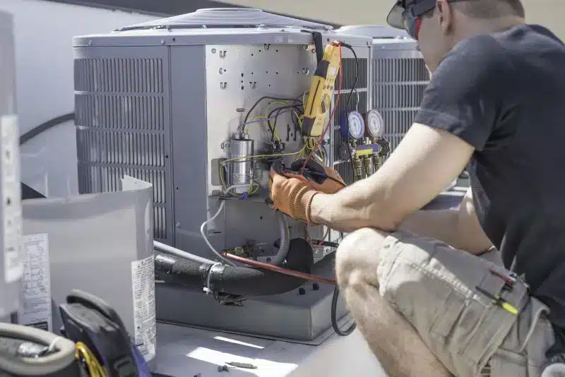 Technician repairing HVAC unit on rooftop.