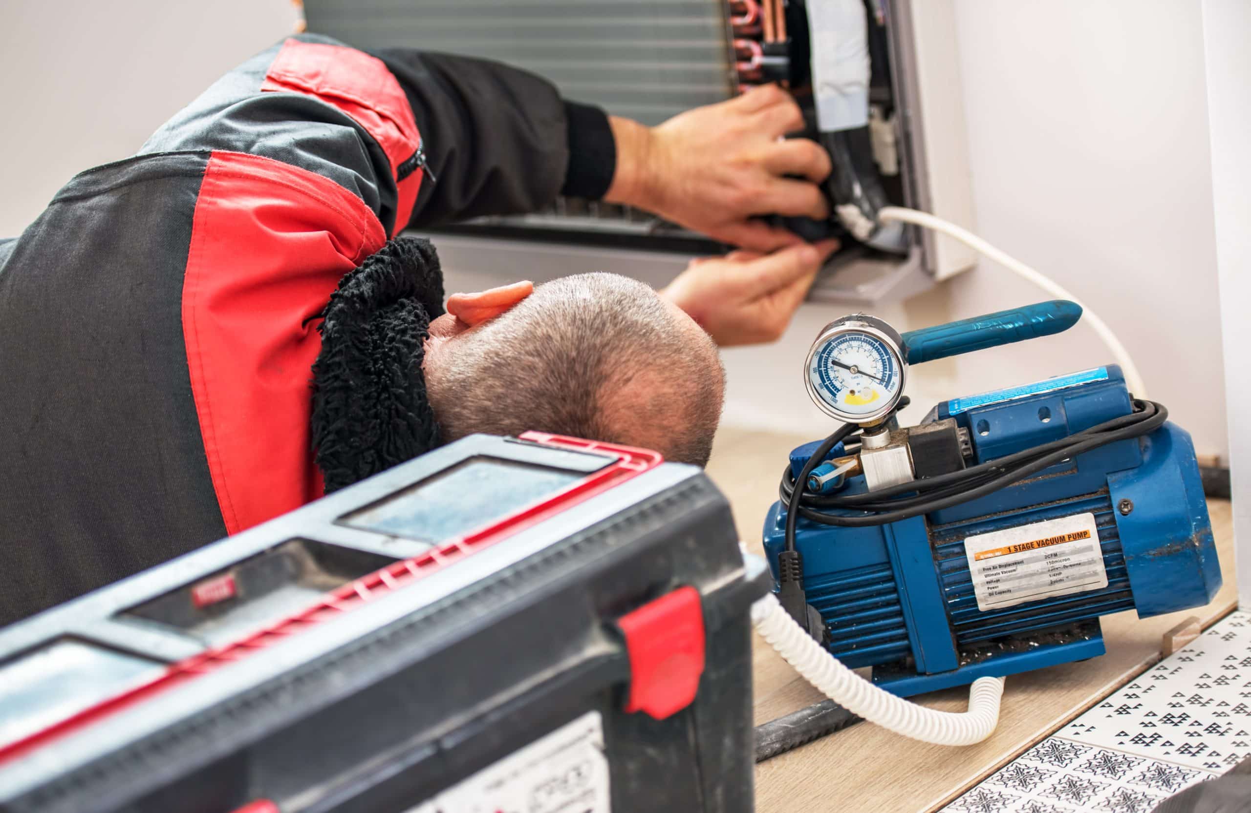 Technician repairing air conditioning unit with tools.