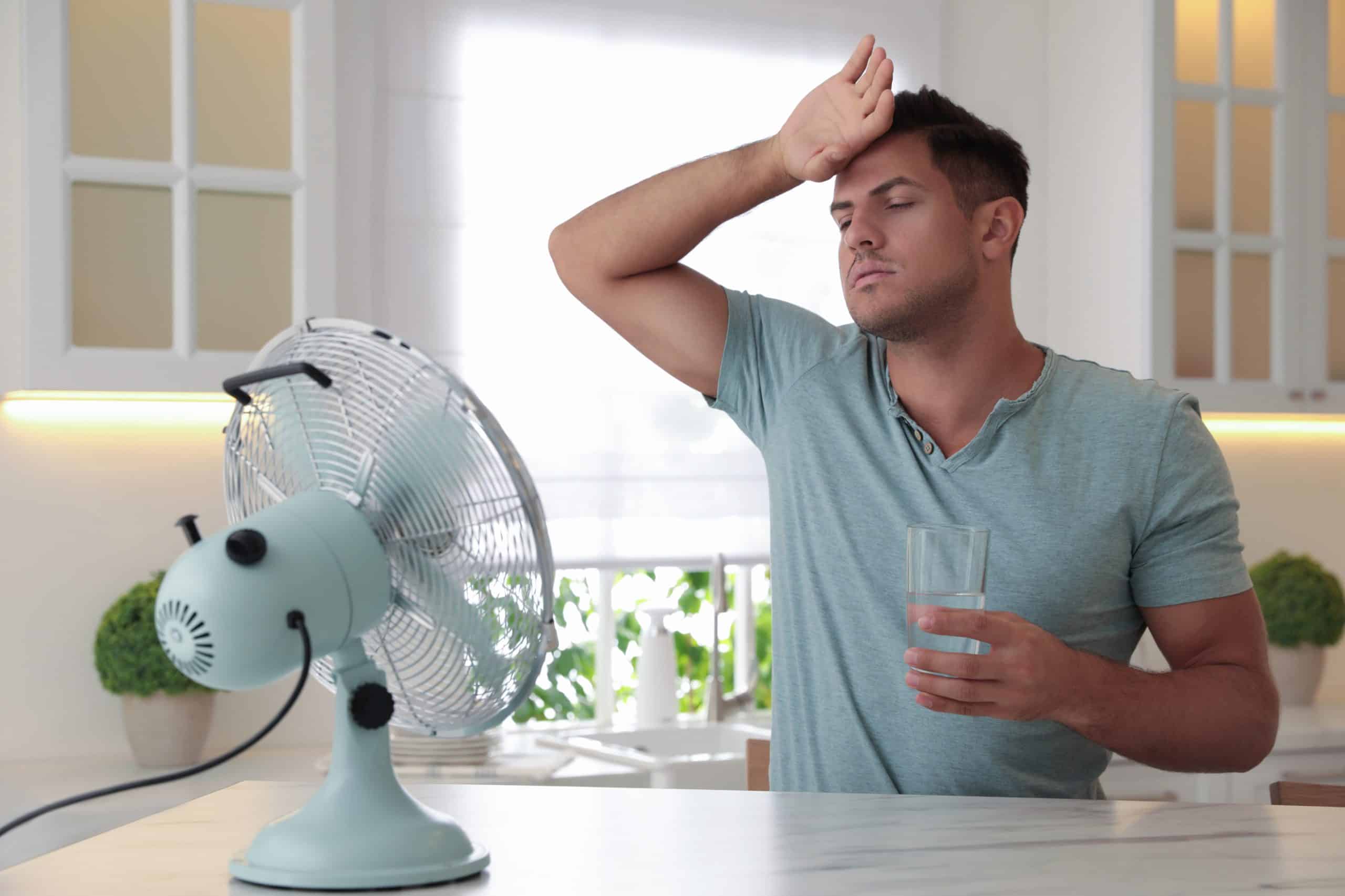 Man cooling off with fan and water