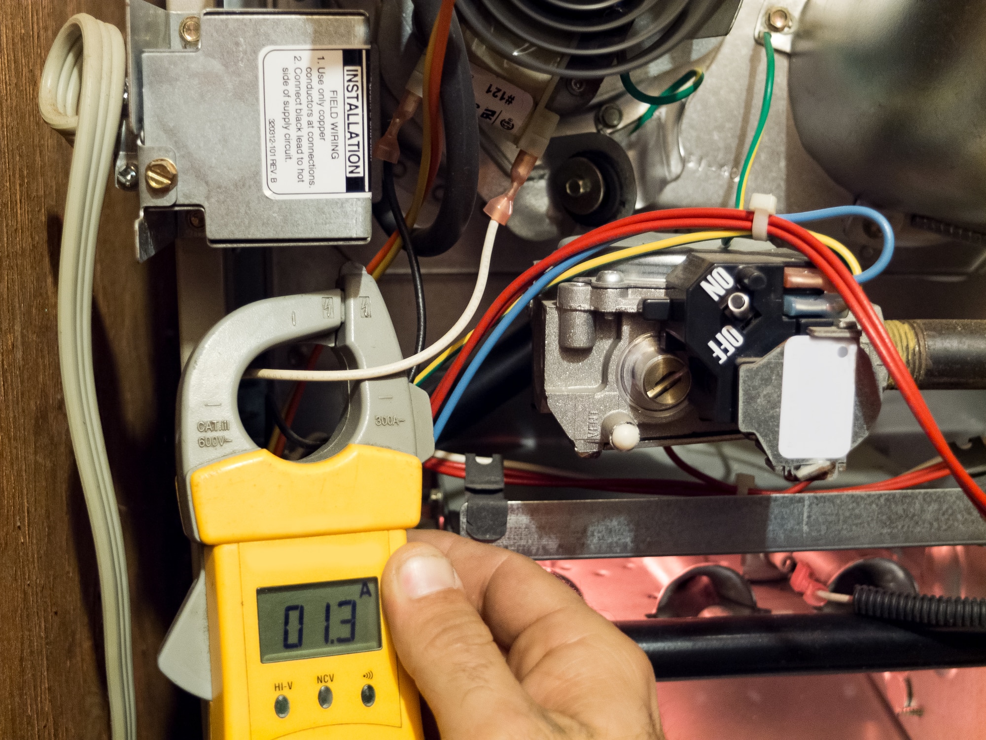 Multimeter measuring electrical current in HVAC system.