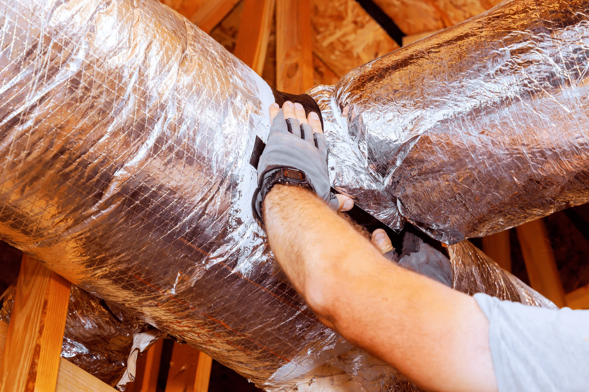 Screenshot 2025-10-27 at 13-54-39 ductwork-repair.jpg (JPEG Image 2500 × 1667 pixels) — Scaled (79%) Technician sealing HVAC duct with foil insulation.