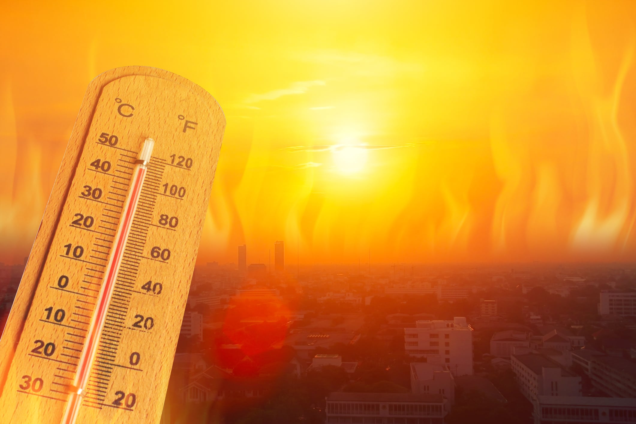 Thermometer in hot urban sunset with heatwaves