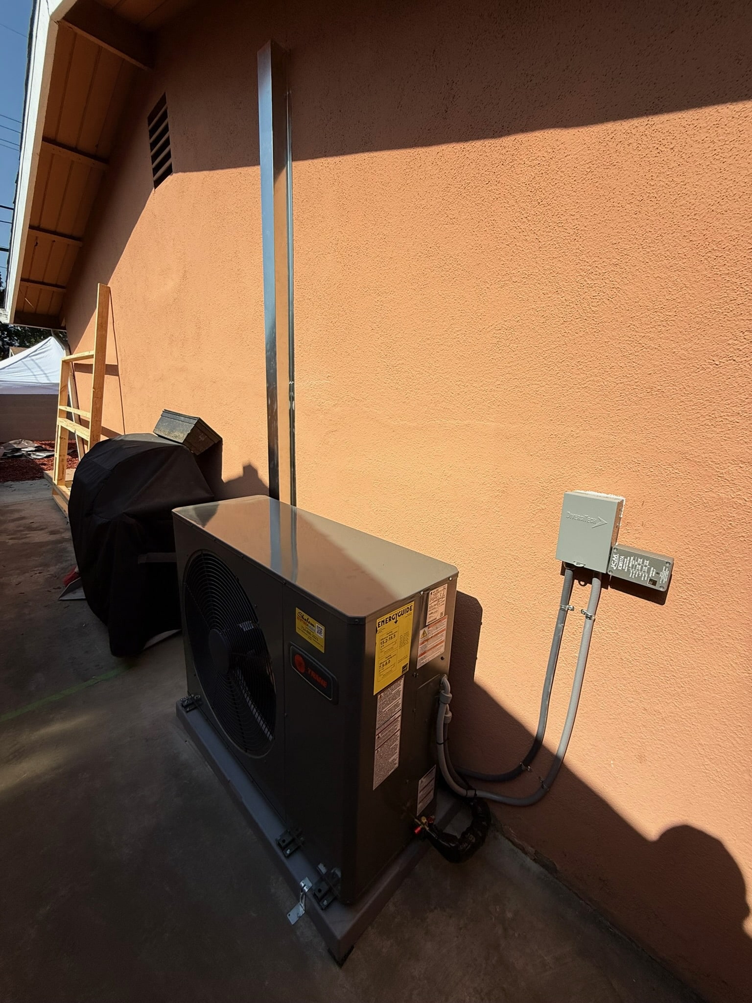 Outdoor HVAC unit beside peach stucco wall