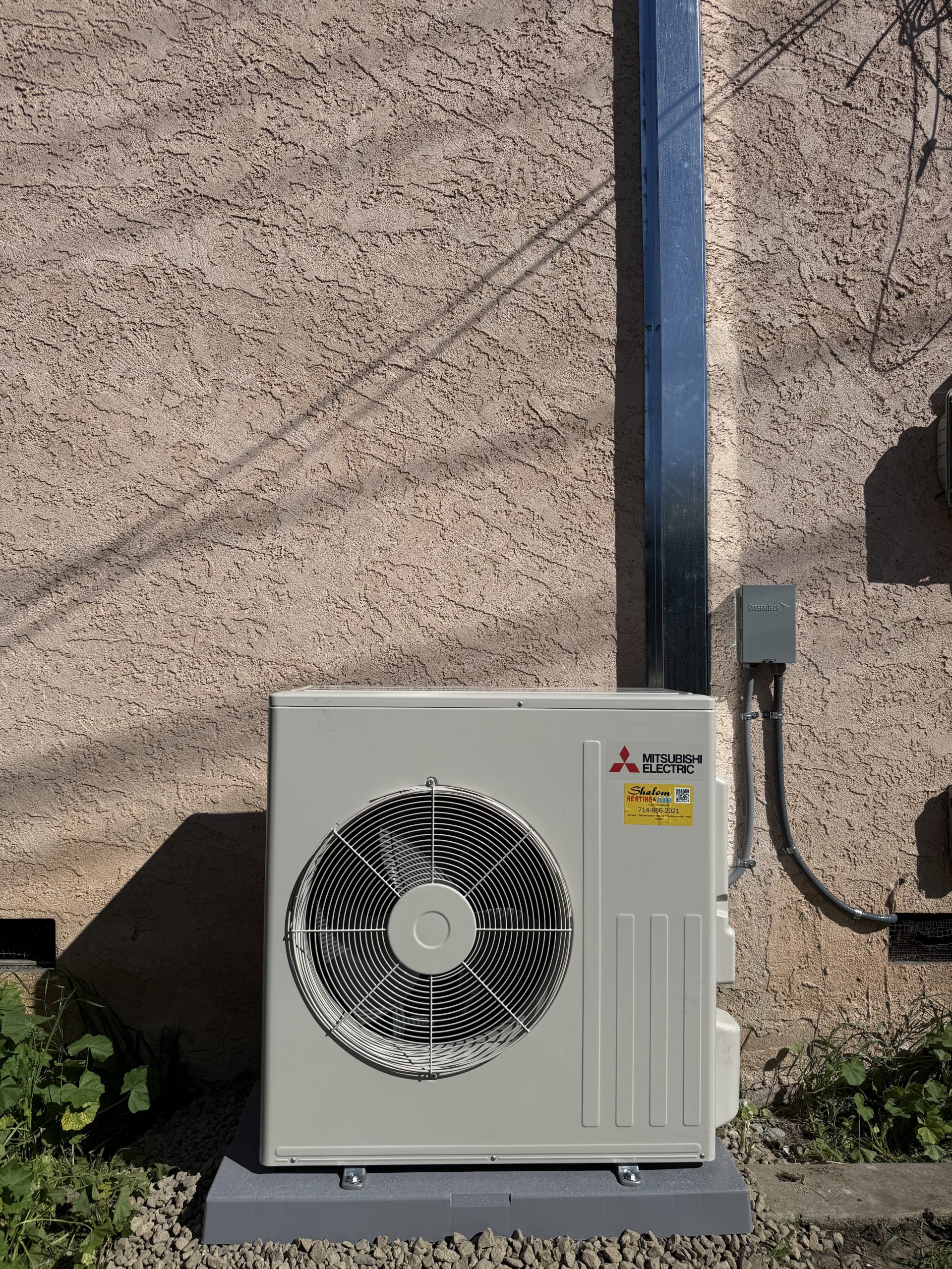Outdoor Mitsubishi Electric air conditioning unit against stucco wall